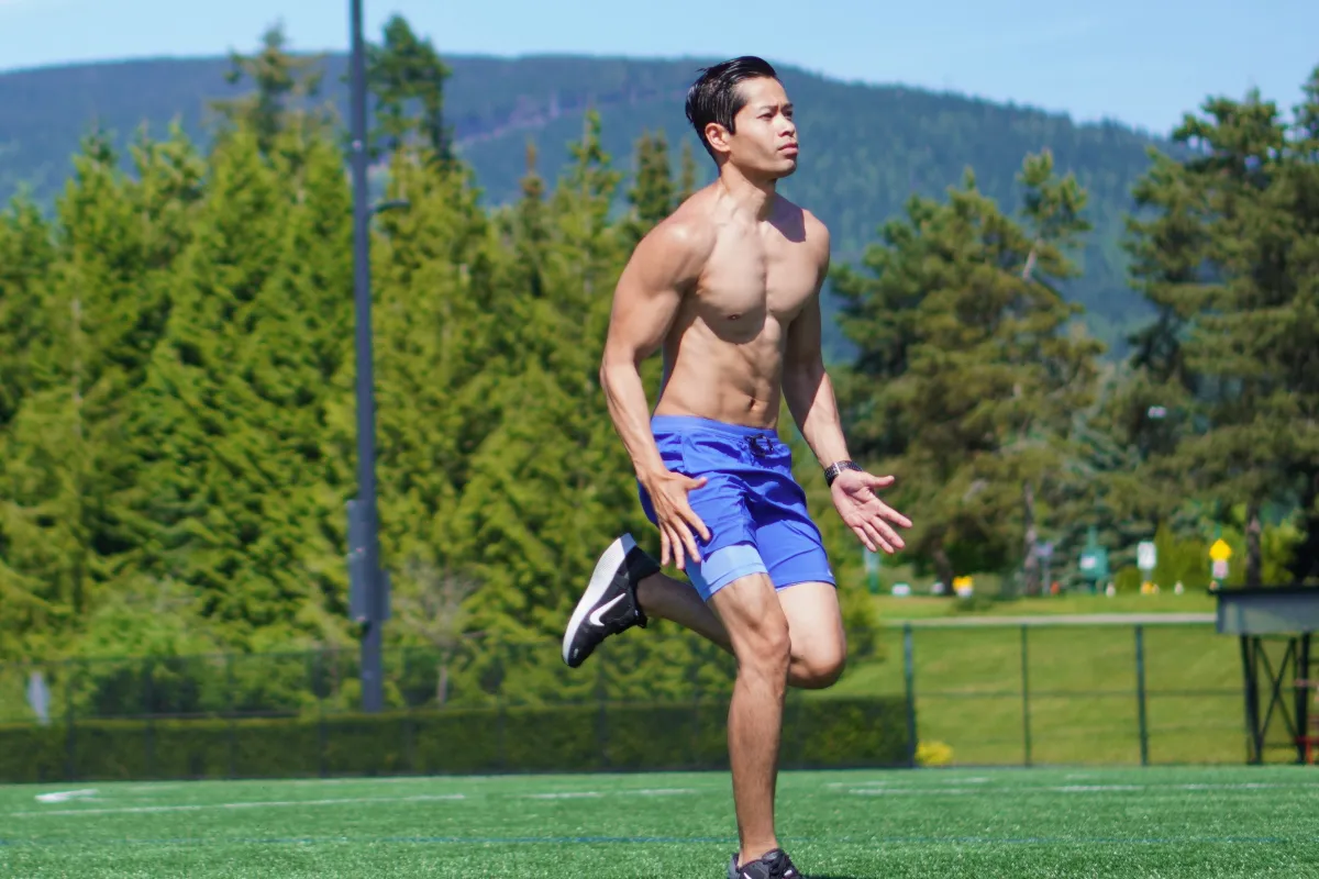 Tee Live showing his high muscle mass percentage as he runs shirtless at the park on a sunny day.