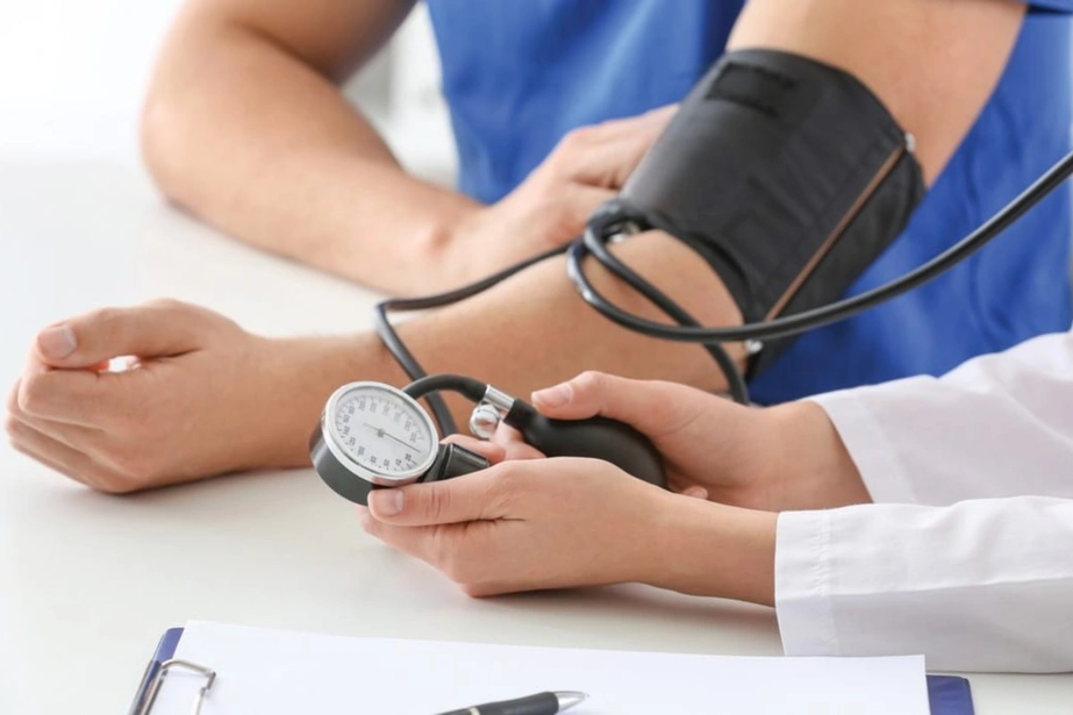 A man is getting his blood pressure checked with a sphygmomanometer by the doctor.